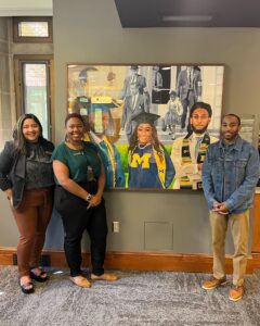 3 Trotter Center staff in front of painting of U-M students